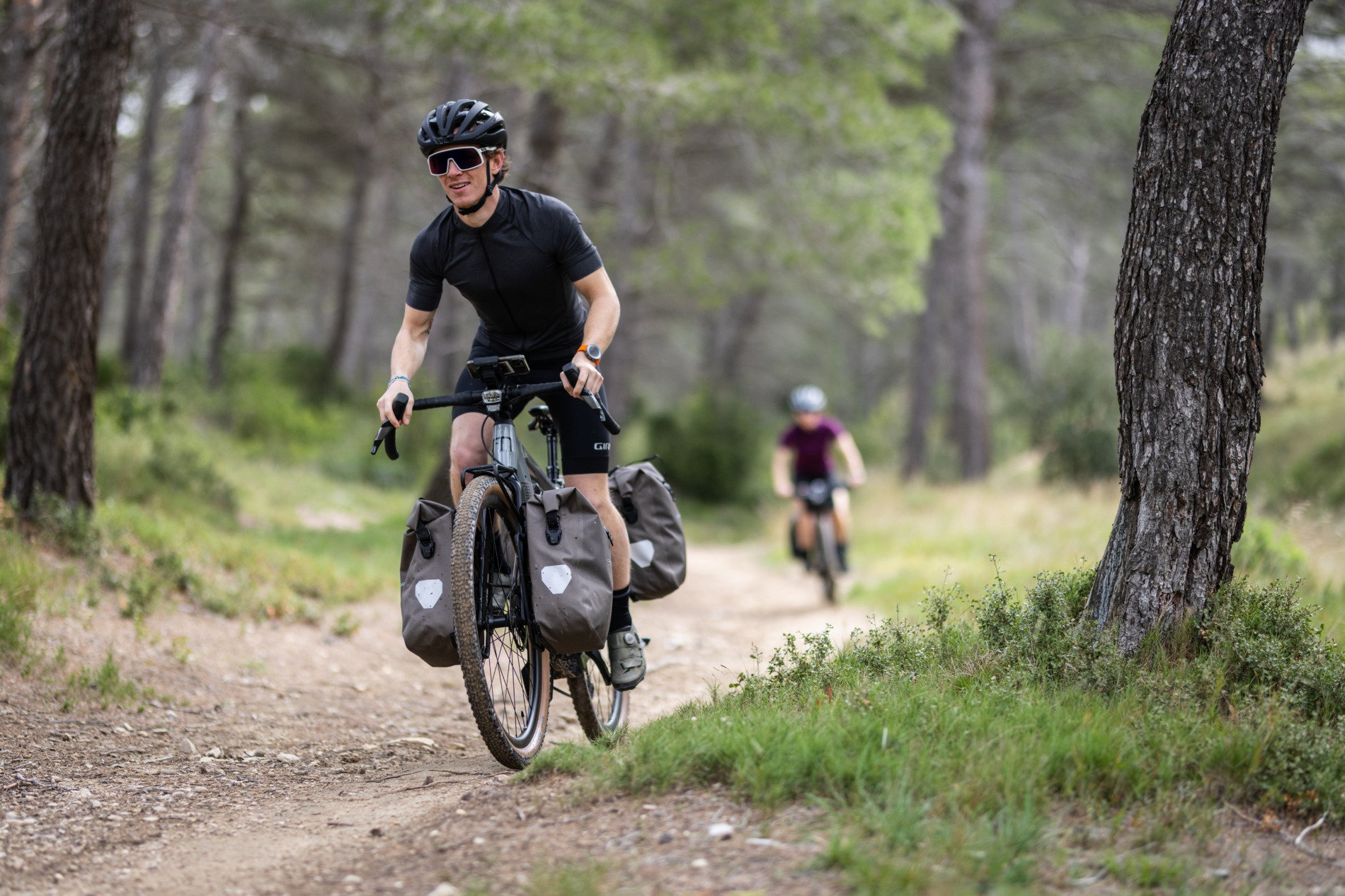 Eim Gravelbiker fährt entspannt aber schnell zwischen Zwei Bäumen daher